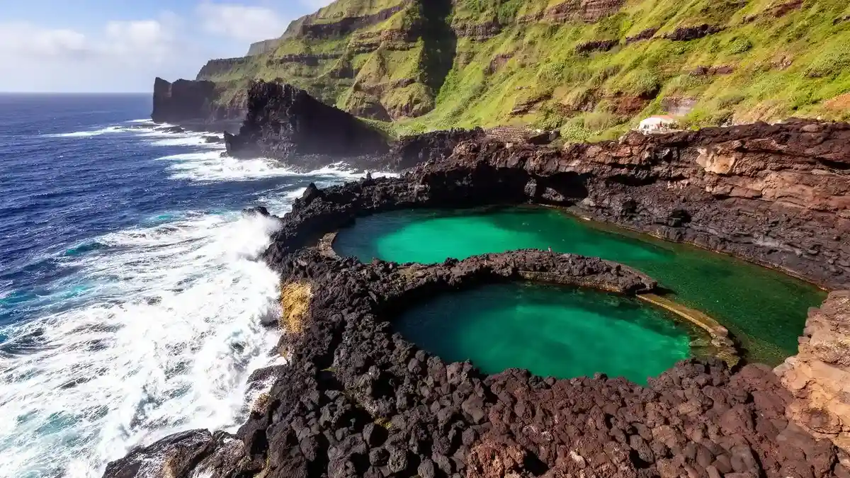 Porto Moniz volcanic natural swimming pools with ocean waves crashing against lava formations